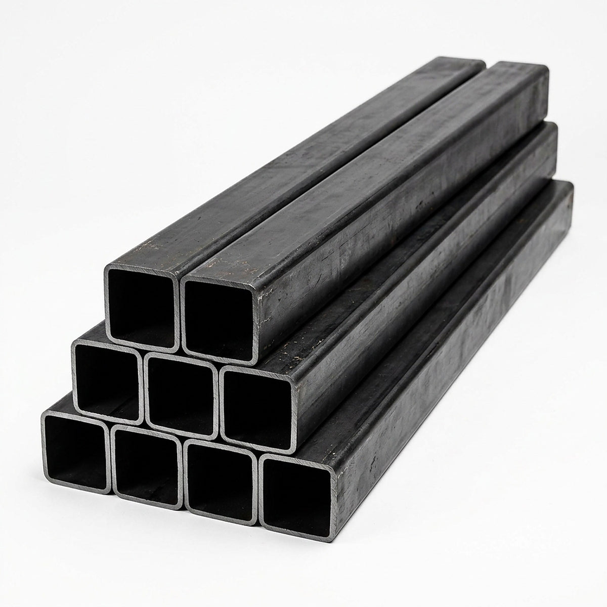 Pila de tubos estructurales cuadrados negros de acero sobre fondo blanco, imagen referencial