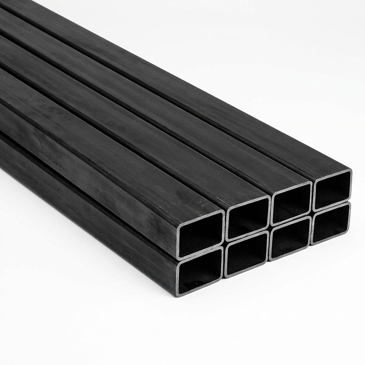 Pila de tubos estructurales rectangulares negros de acero sobre fondo blanco, imagen referencial