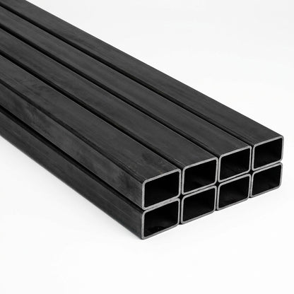 Pila de tubos estructurales rectangulares negros de acero sobre fondo blanco, imagen referencial